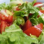 A salad with green leaf lettuce, tomatoes and onions