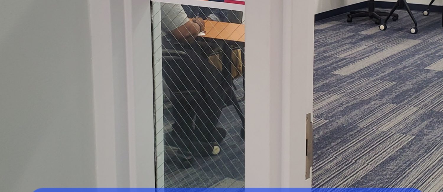 Picture of door from hallway. A sign in the window says "Interviews" and the words "Interview in progress" are in an overlay towards the bottom.
