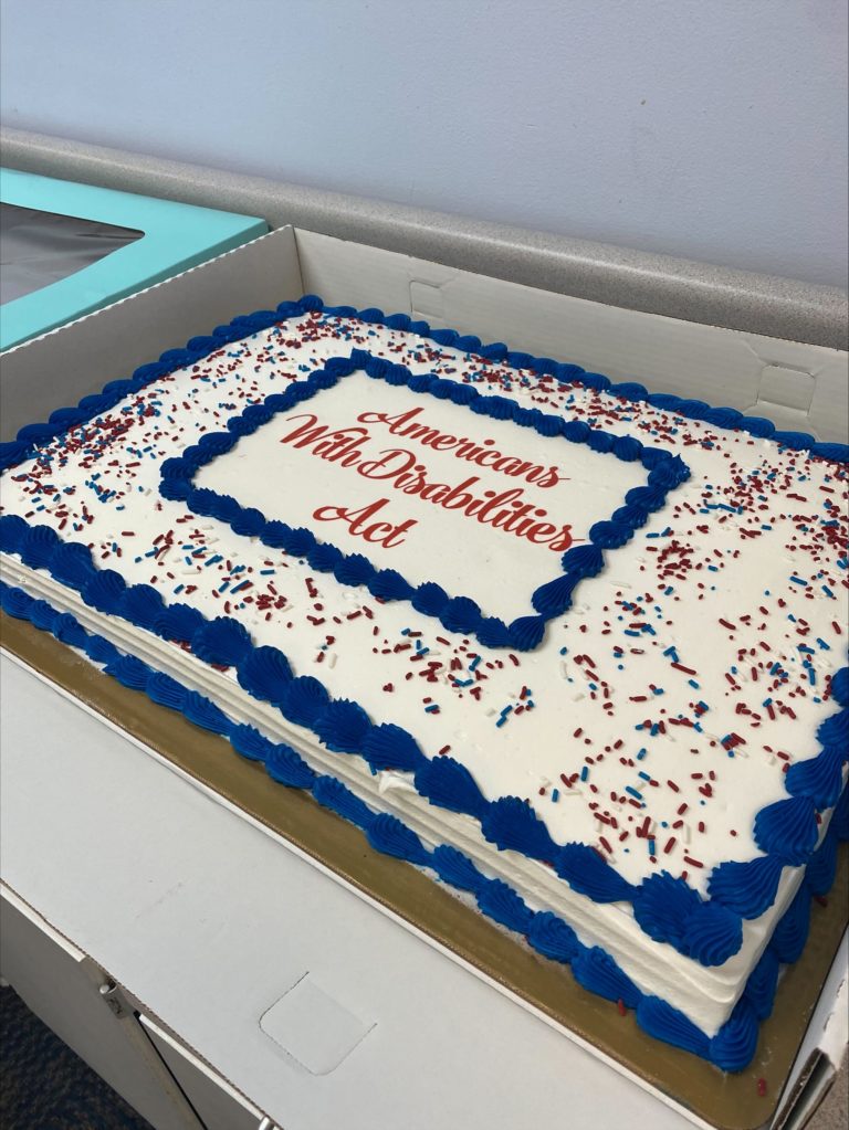 Large cake with white frosting and blue lettering that reads "Americans with Disabilities Act"