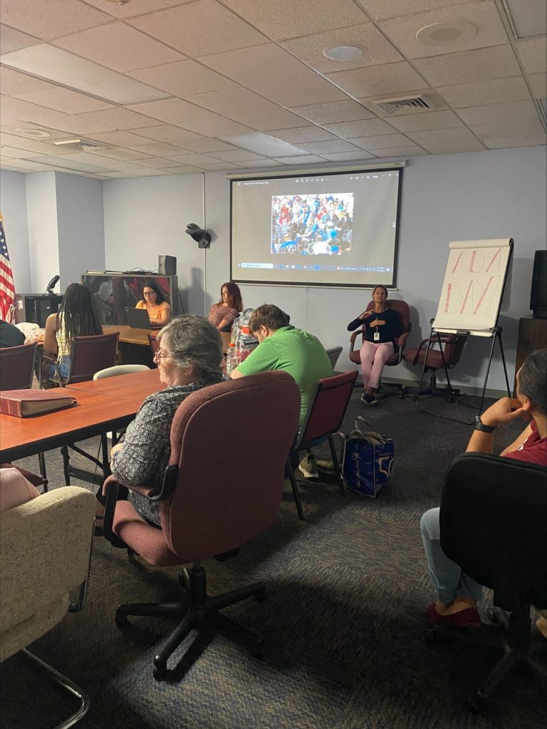 A group of ECI staff and participants view a presentation of pictures from ECI's presence at a march in Washington D.C. in support of the ADA.
