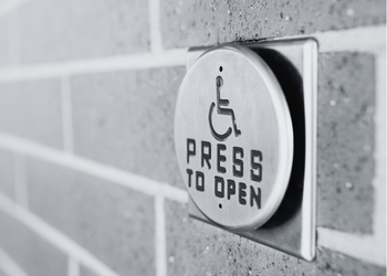 A close-up of a "Press to Open" button to activate an accessible door.
